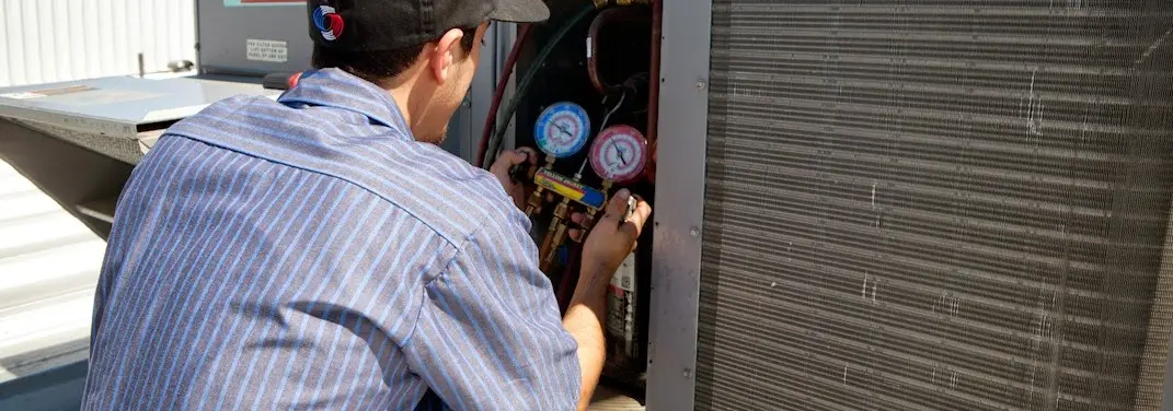 HVAC technician servicing a condenser unit in Hermon