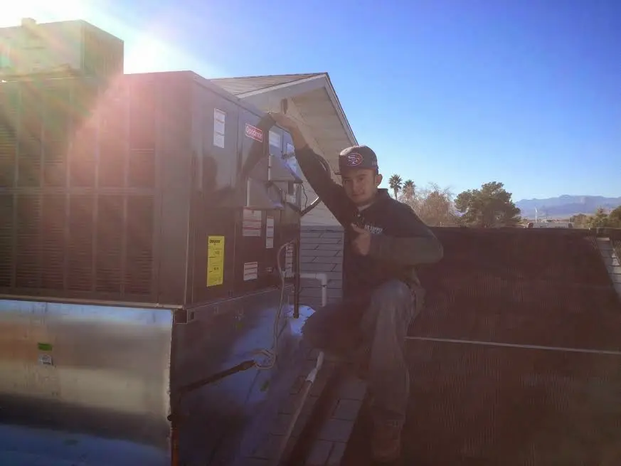 HVAC technician performing Air Duct Cleaning on a rooftop unit in Hermon
